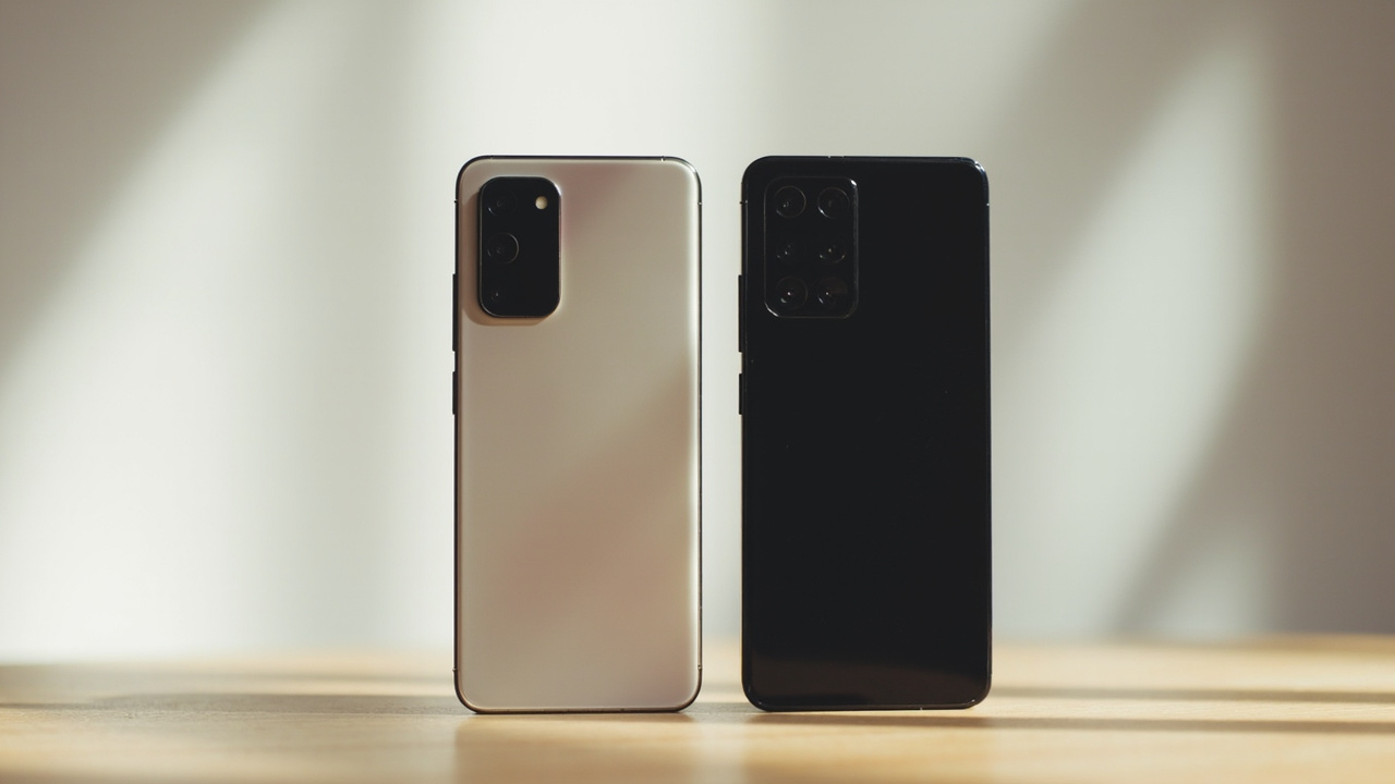 Side-by-side view of two phones from the back, one with anti-reflective display, both on a clean desk, soft studio lighting